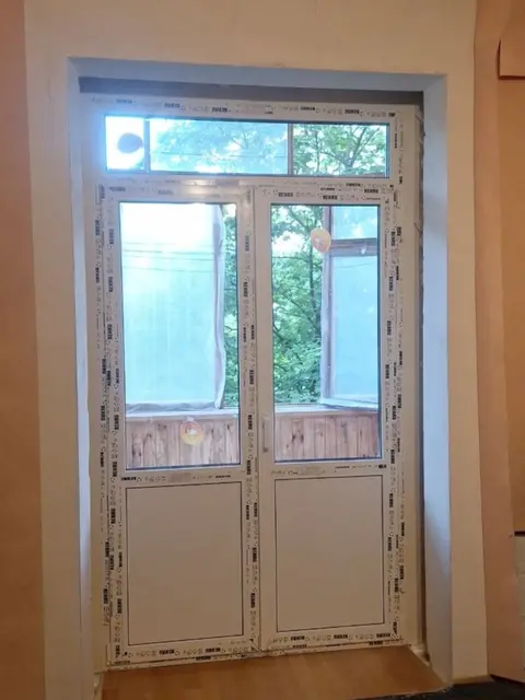 Нові балконні двері Rehau Euro 70 з фрамугою після завершення монтажу в квартирі.