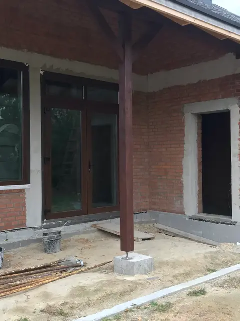 Вхідні двері та вікна Aluplast у ламінації «горіх» на задньому фасаді заміського будинку.