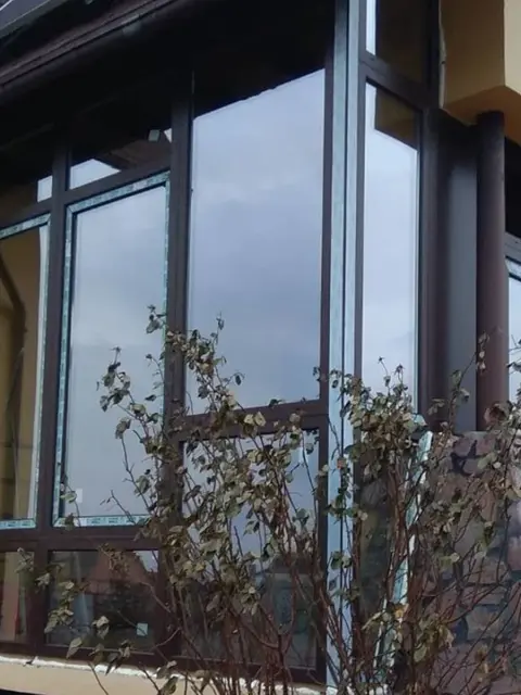 Кутове скління тераси з профілю WDS 5S у ламінації «темний дуб» з інтеграцією конструкцій у покрівлю.