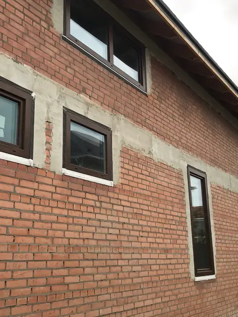 Невеликі вікна Aluplast у ламінації «горіх» на бічному фасаді заміського будинку.