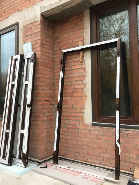 Відкидні стулки Aluplast у ламінації «горіх» перед встановленням у заміському будинку.